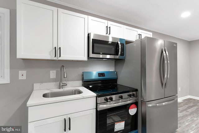 kitchen with appliances with stainless steel finishes, sink, white cabinets, and light stone counters