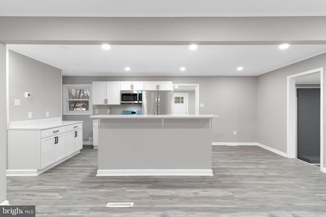 kitchen featuring white cabinetry, stainless steel appliances, a center island, and light hardwood / wood-style flooring