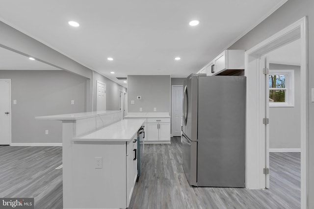 kitchen with appliances with stainless steel finishes, white cabinetry, a kitchen bar, kitchen peninsula, and light wood-type flooring