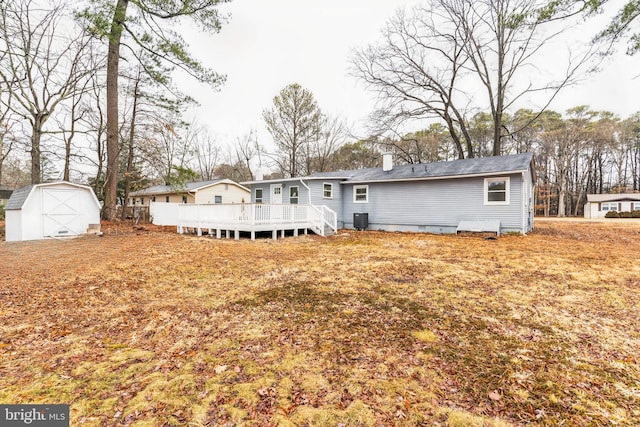 rear view of property featuring a wooden deck, central air condition unit, and a storage unit