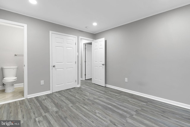 unfurnished bedroom with hardwood / wood-style flooring, connected bathroom, and a closet