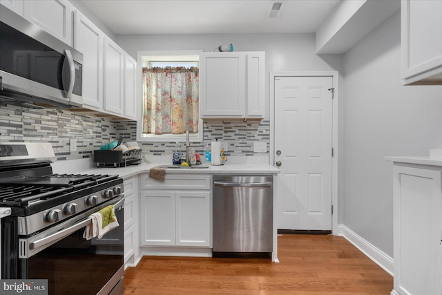 kitchen with white cabinets, light wood-type flooring, stainless steel appliances, and sink