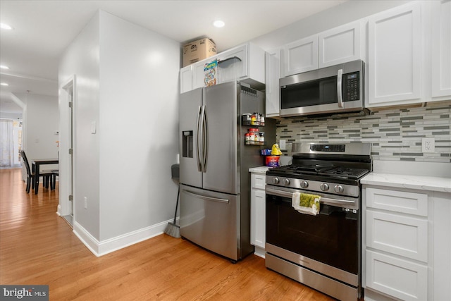 kitchen with tasteful backsplash, appliances with stainless steel finishes, light hardwood / wood-style floors, and white cabinets