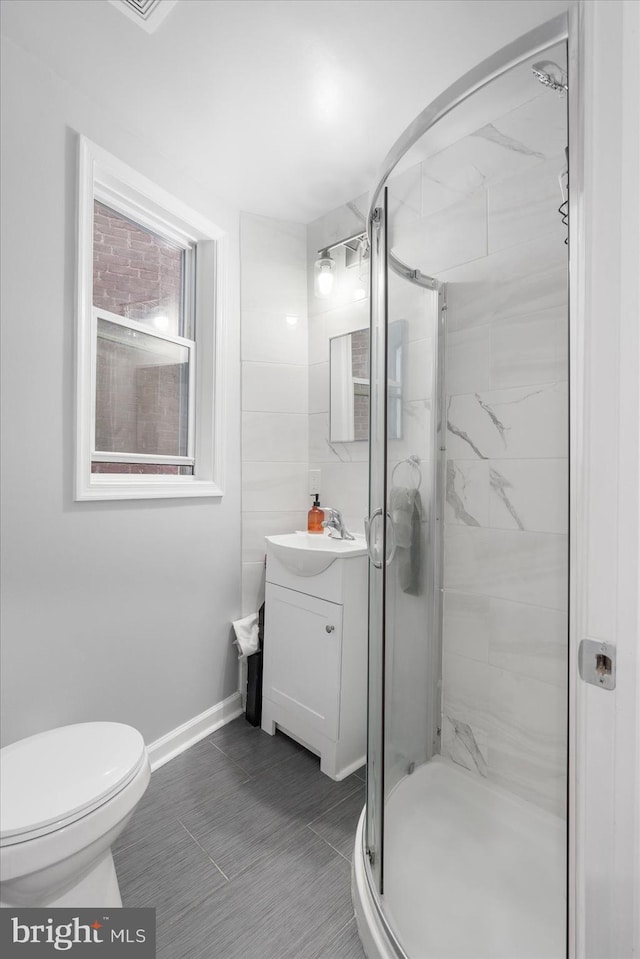 bathroom with vanity, tile patterned floors, toilet, and a shower with door