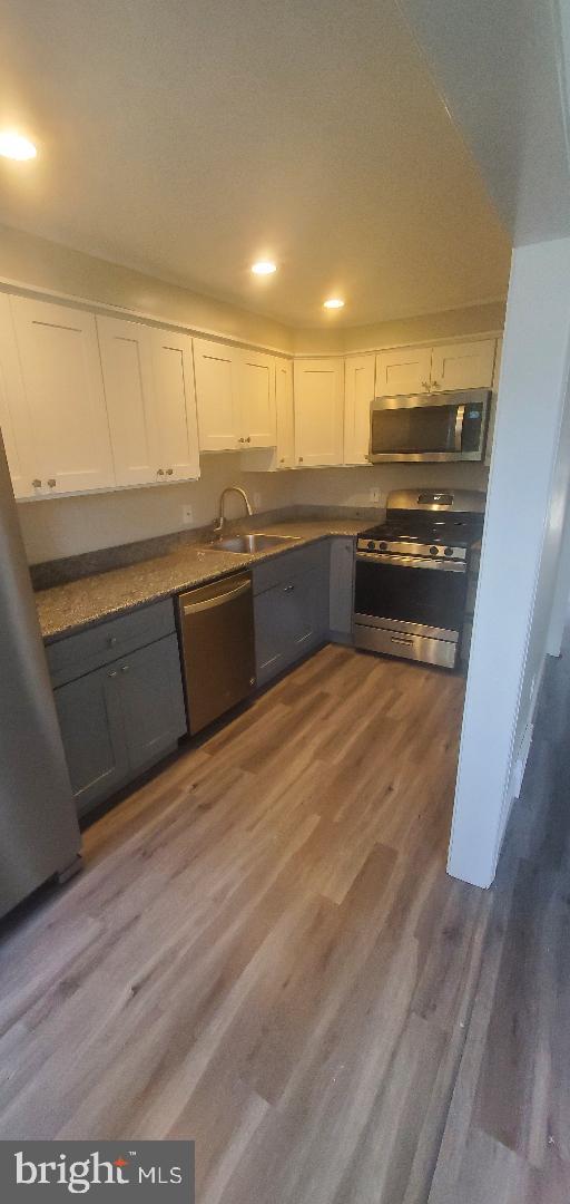 kitchen featuring white cabinetry, stainless steel appliances, dark wood-type flooring, and sink