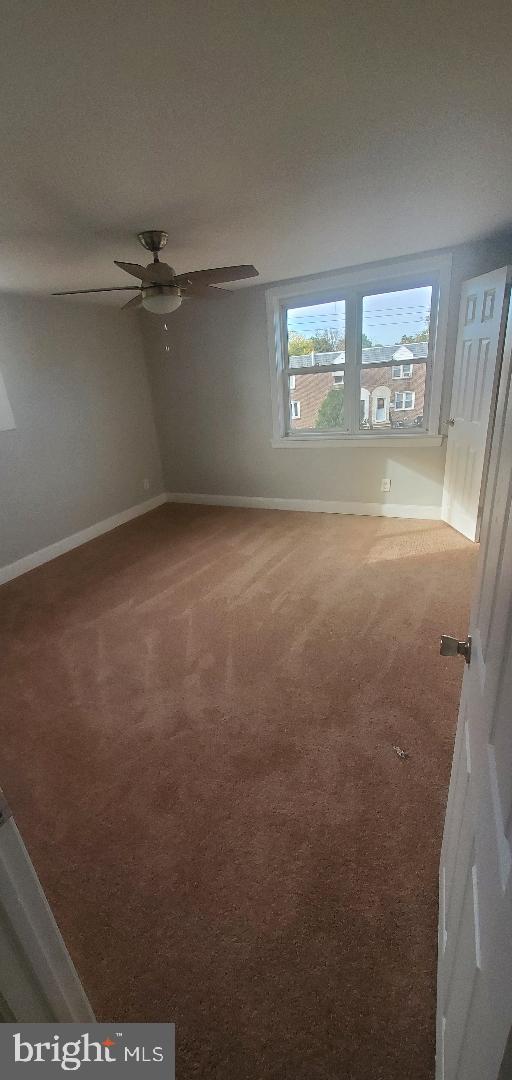 carpeted spare room with ceiling fan