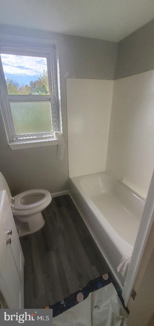 bathroom featuring toilet, a bathing tub, and wood-type flooring