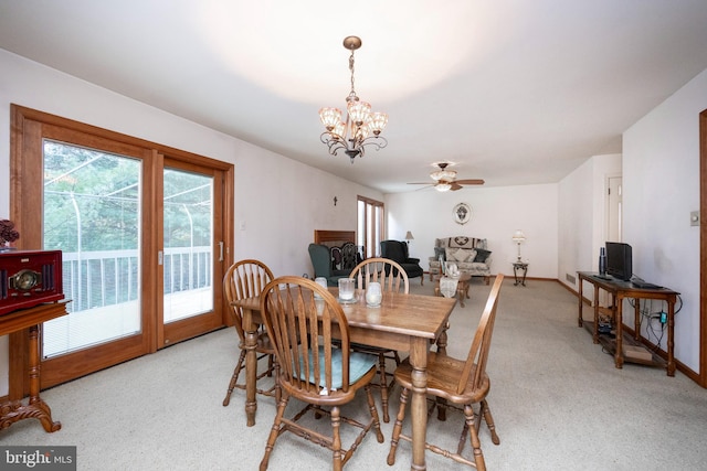 dining area with ceiling fan with notable chandelier and light colored carpet