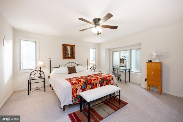 bedroom featuring multiple windows, light colored carpet, and ceiling fan