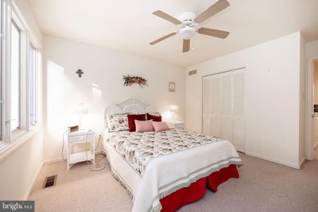 carpeted bedroom featuring a closet, multiple windows, and ceiling fan