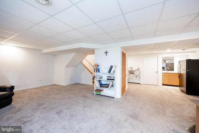 interior space with a paneled ceiling, carpet, and stainless steel fridge