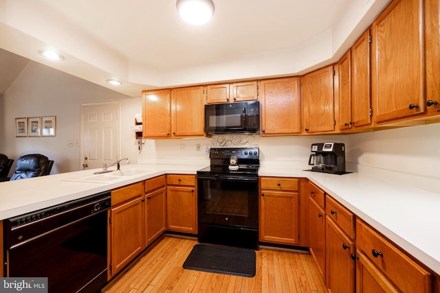 kitchen with light wood-type flooring, black appliances, kitchen peninsula, and lofted ceiling