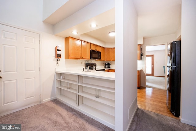 kitchen with black appliances, kitchen peninsula, and light carpet