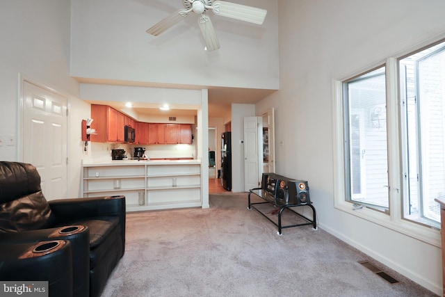 living room featuring a high ceiling, light colored carpet, and plenty of natural light