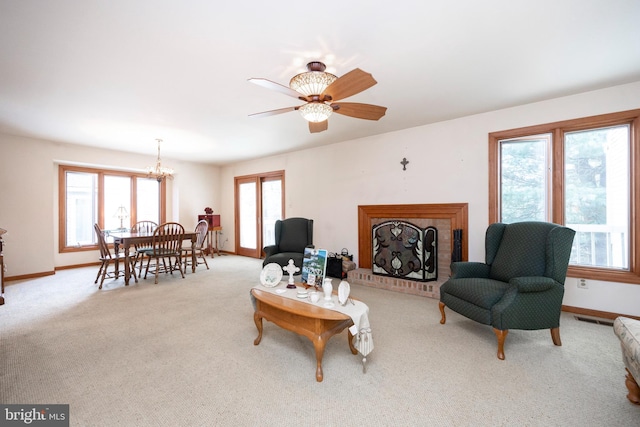 carpeted living room featuring ceiling fan with notable chandelier