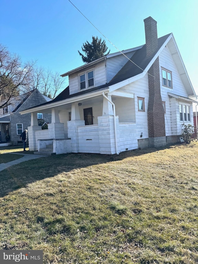 view of front of house featuring a chimney, a porch, and a front yard