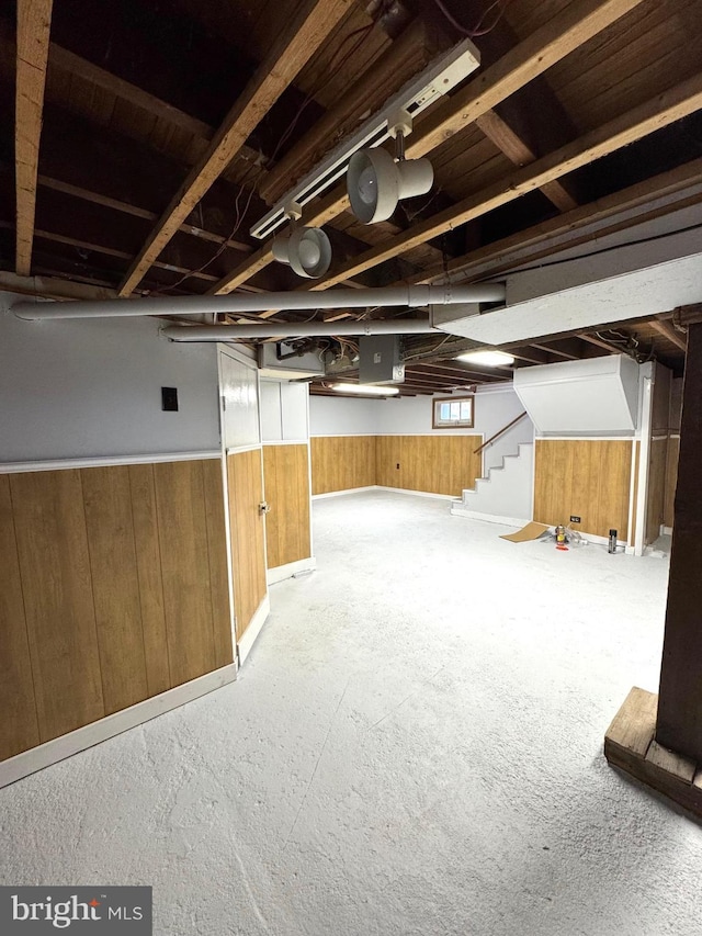 basement featuring wainscoting, wooden walls, and stairs