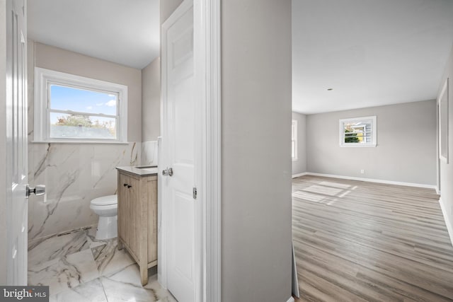 bathroom featuring vanity, a shower, toilet, tile walls, and wood-type flooring