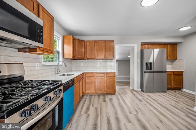 kitchen featuring backsplash, sink, light hardwood / wood-style floors, and appliances with stainless steel finishes