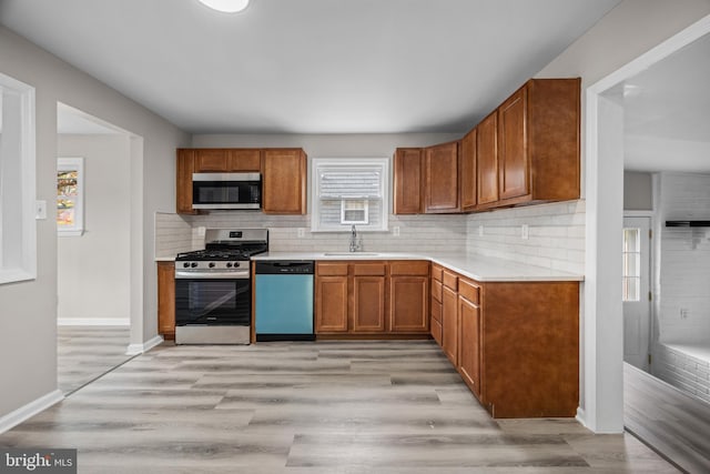 kitchen with decorative backsplash, appliances with stainless steel finishes, light wood-type flooring, and sink