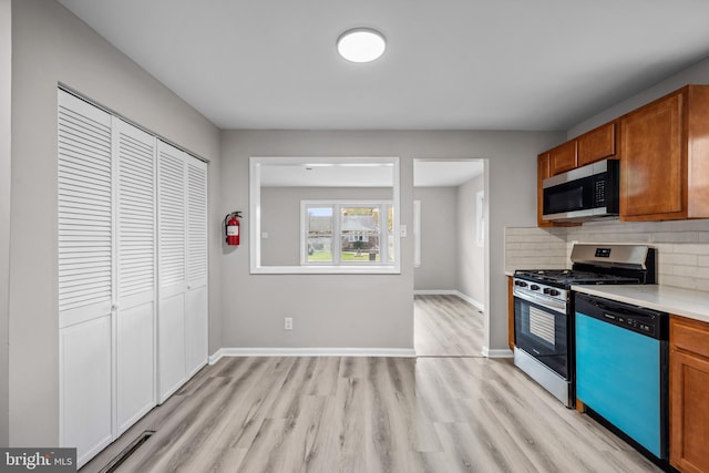 kitchen with tasteful backsplash, stainless steel appliances, and light wood-type flooring