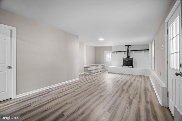 unfurnished living room with a wood stove and light hardwood / wood-style flooring