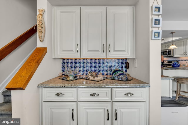 interior space featuring pendant lighting, stone countertops, white cabinetry, and backsplash