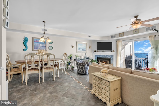 living room featuring a fireplace, ceiling fan, and dark tile patterned flooring