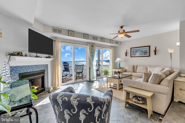 living room featuring a tiled fireplace and ceiling fan