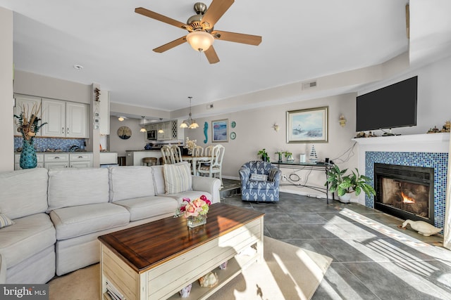 living room featuring a tiled fireplace and ceiling fan