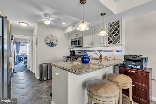 kitchen with stainless steel appliances, sink, a breakfast bar, light stone counters, and decorative backsplash