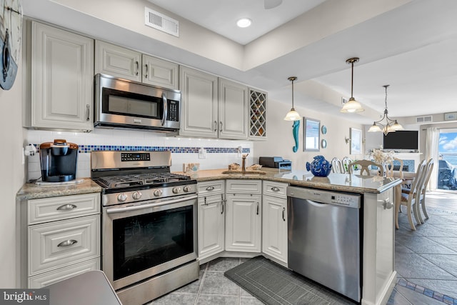 kitchen with kitchen peninsula, hanging light fixtures, decorative backsplash, and appliances with stainless steel finishes