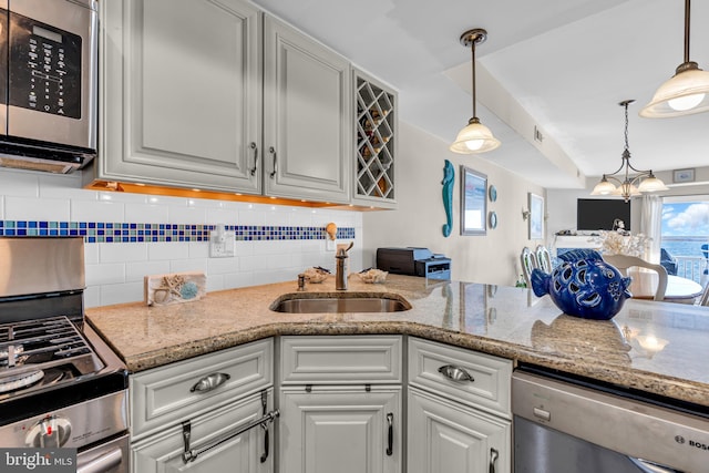 kitchen with appliances with stainless steel finishes, a notable chandelier, sink, and decorative light fixtures