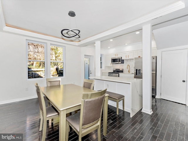 dining room featuring crown molding, dark hardwood / wood-style flooring, sink, and a tray ceiling