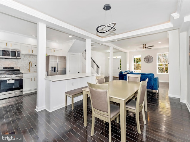 dining area featuring ornamental molding, ceiling fan, dark wood-type flooring, and sink