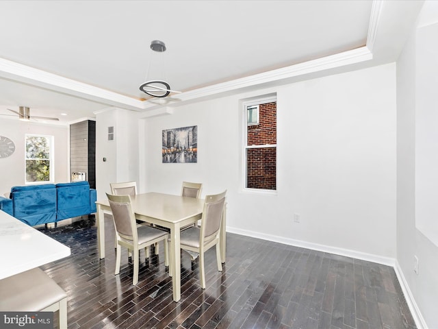 dining area featuring a tray ceiling, crown molding, ceiling fan, and dark wood-type flooring