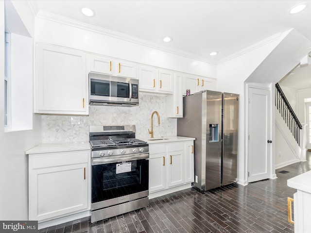 kitchen with appliances with stainless steel finishes, dark hardwood / wood-style flooring, white cabinetry, and sink