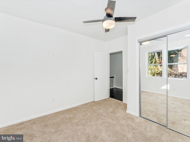 unfurnished bedroom featuring ceiling fan, light colored carpet, and a closet