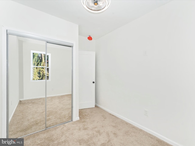 unfurnished bedroom featuring light carpet and a closet