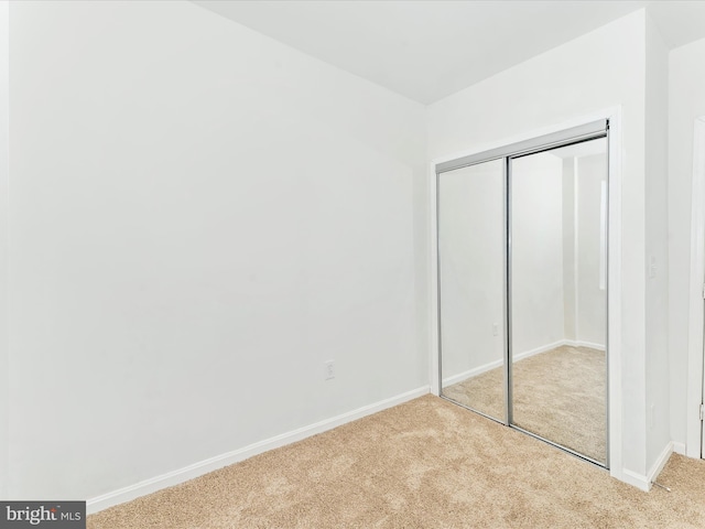 unfurnished bedroom with light carpet and a closet