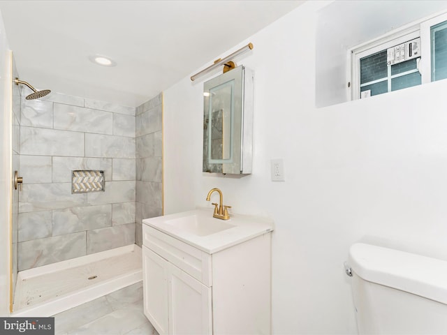 bathroom with tiled shower, vanity, and toilet