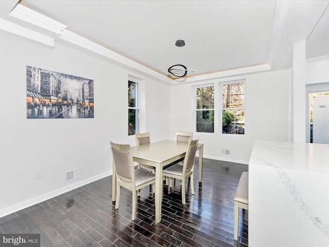 dining area featuring ornamental molding, a raised ceiling, and dark wood-type flooring