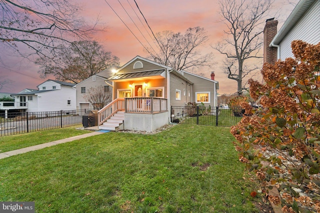 back house at dusk featuring a porch and a lawn