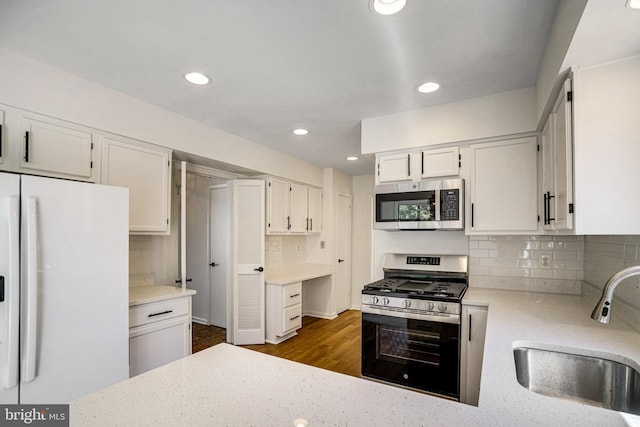 9103 Home Guard Dr, Burke, VA 22015 - kitchen featuring appliances with stainless steel finishes, a sink, decorative backsplash, white cabinets, and light stone countertops