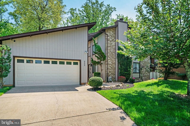 9103 Home Guard Dr, Burke, VA 22015 - mid-century home featuring concrete driveway, a chimney, a front lawn, and an attached garage