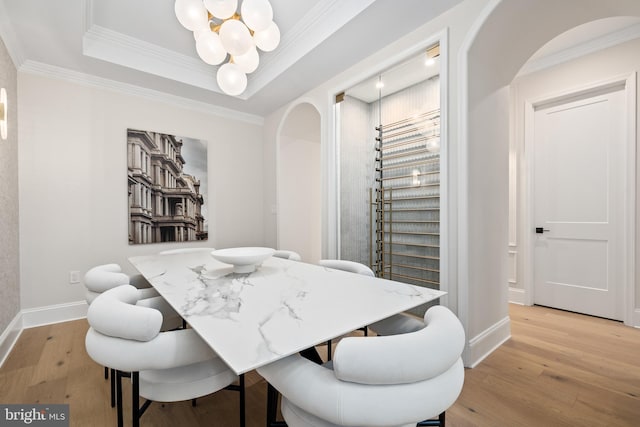 dining room with an inviting chandelier, ornamental molding, and light hardwood / wood-style flooring