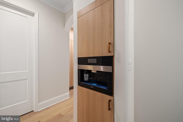 interior details featuring ornamental molding, light brown cabinets, oven, and light hardwood / wood-style floors