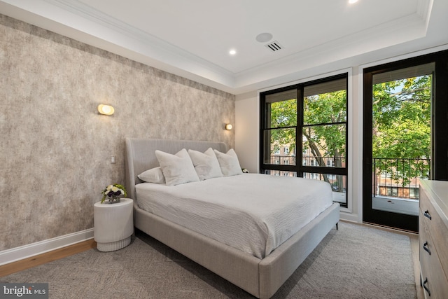 bedroom featuring access to exterior, light hardwood / wood-style flooring, crown molding, and a tray ceiling