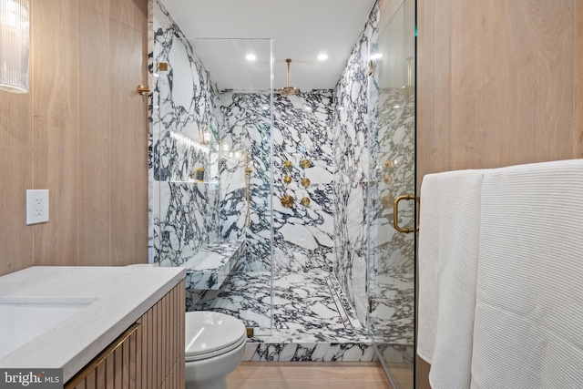 bathroom with walk in shower, tile walls, vanity, and toilet