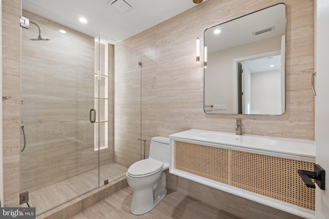 bathroom with walk in shower, vanity, toilet, and tile walls